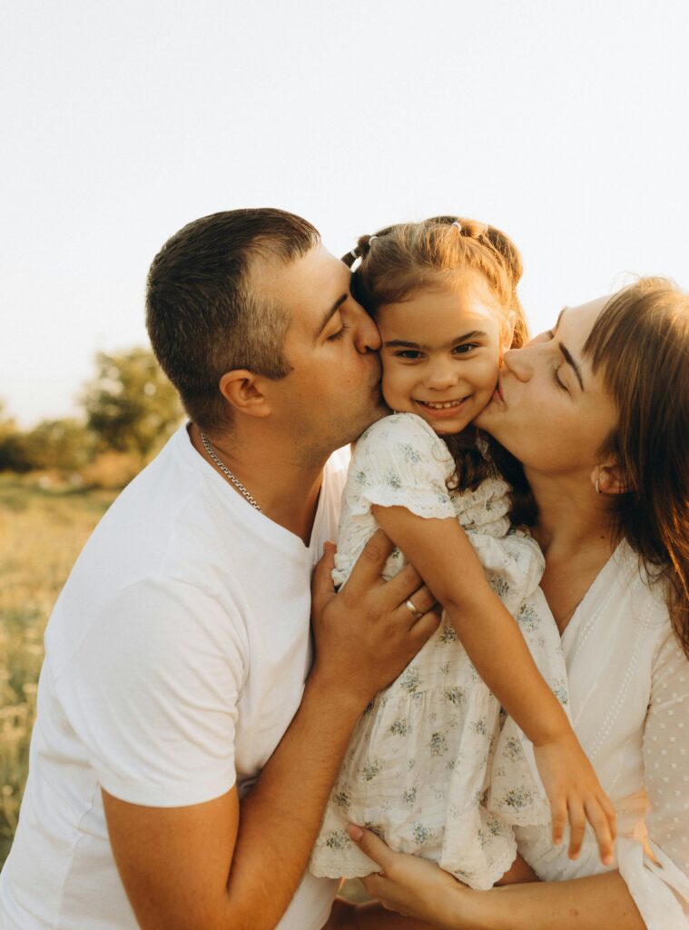 A happy family of three sharing a joyful moment outdoors in summer.